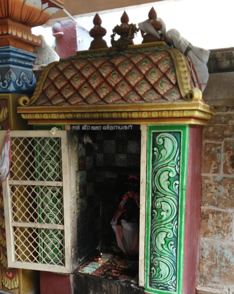 Tiny shrine with mesh door, green scrollwork and a lamp inside