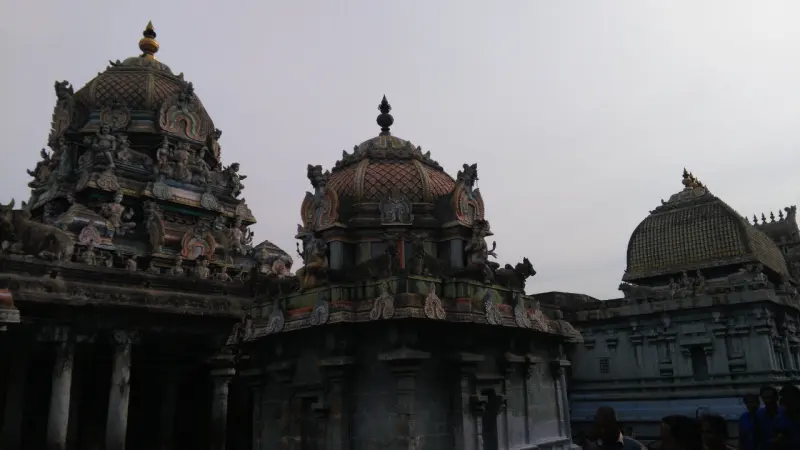 Domed shrine roofs with carved figures under a grey sky, a golden-patterned dome at the right.