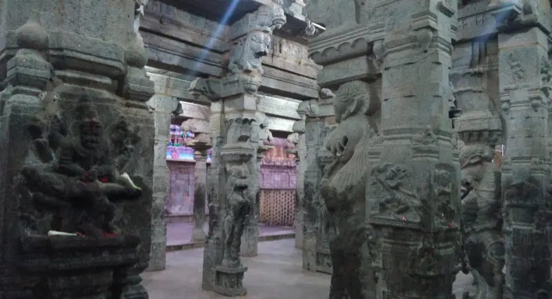 Stone pillars carved with mythical beasts and sculpted figures inside a dimly lit hall