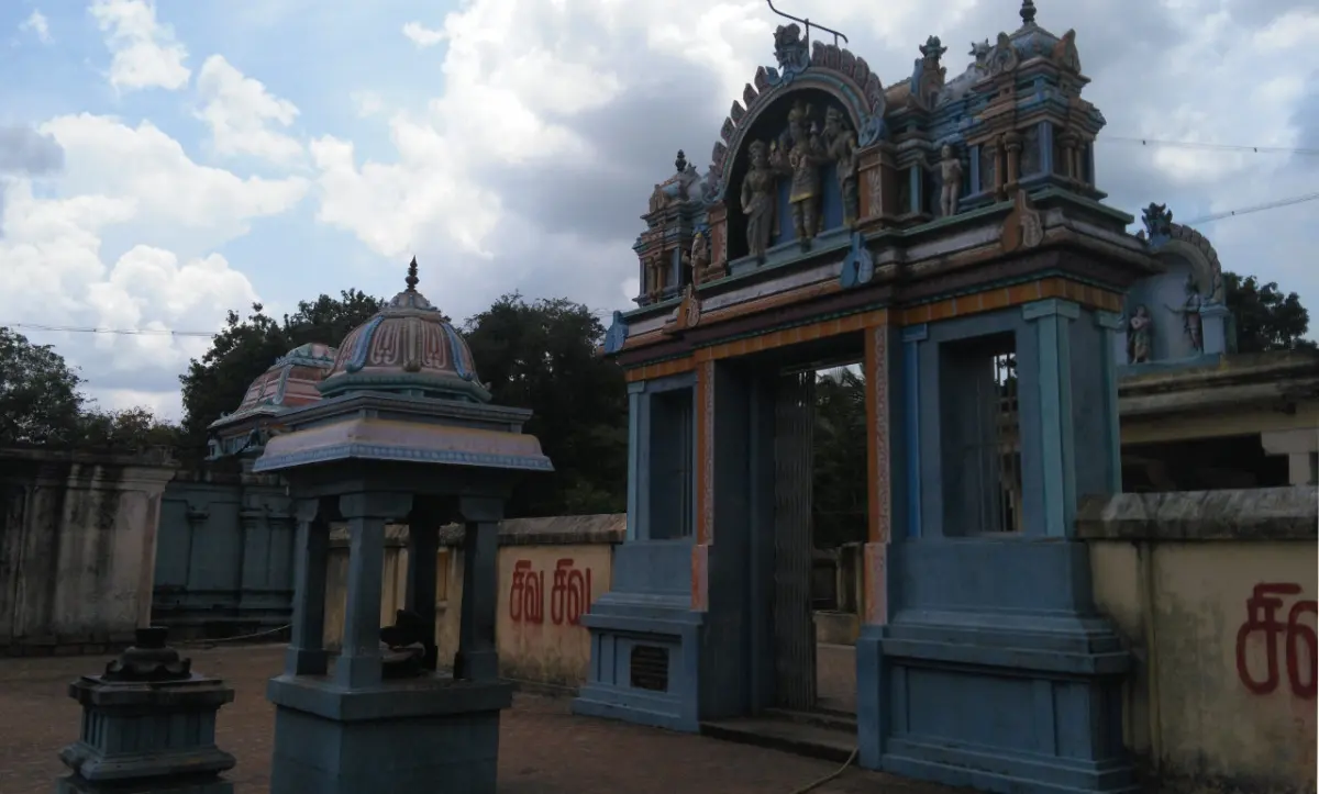 A blue gateway with a painted tower, with a small domed shrine beside it