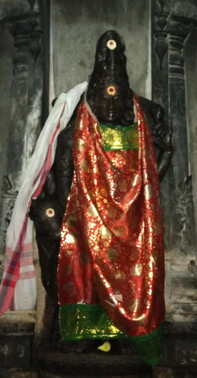 A dark stone idol in a red silk cloth
