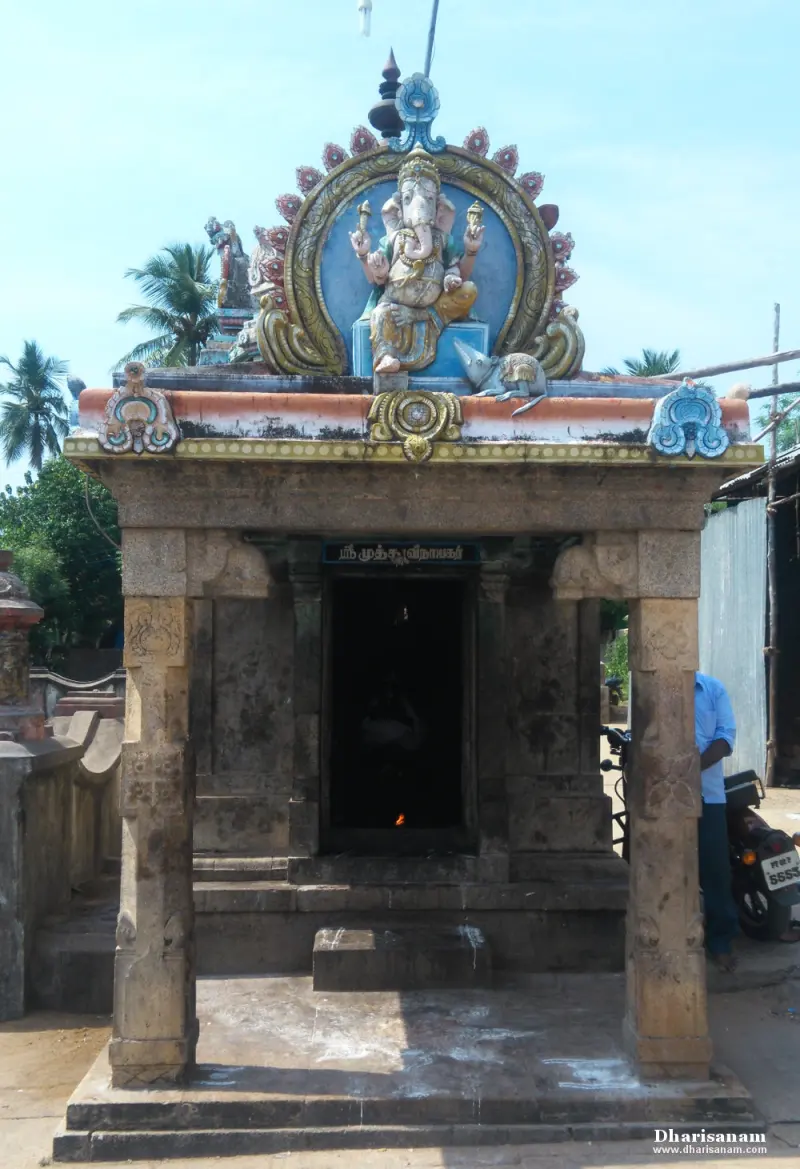 Small stone shrine with a painted Vinayakar figure on its roof and a name board over the door