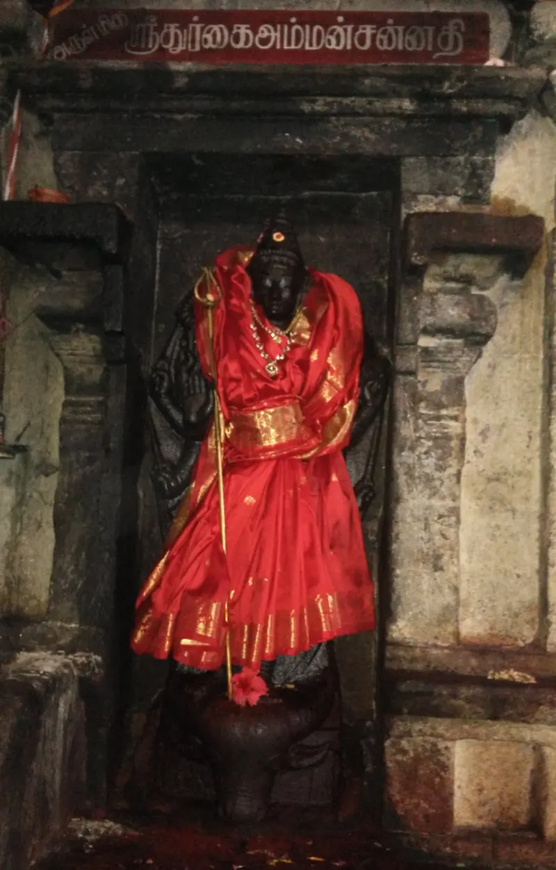 A black stone goddess draped in red silk, with a name board above the shrine