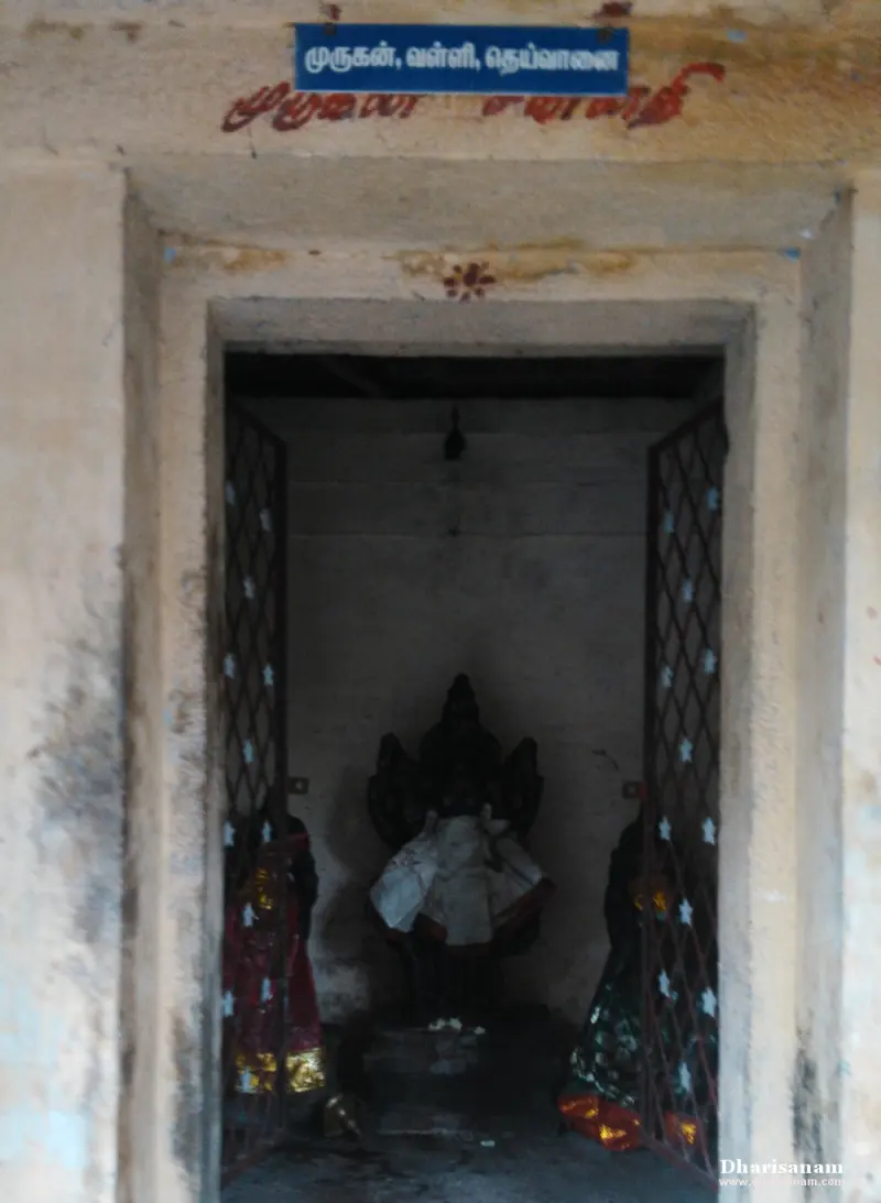 A dark idol with robed figures on either side, seen through iron gates; a blue board names Murugan, Valli and Deivanai.