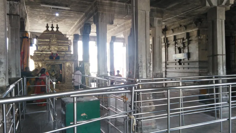 Devotees in railed queues before a small gold shrine in the hall