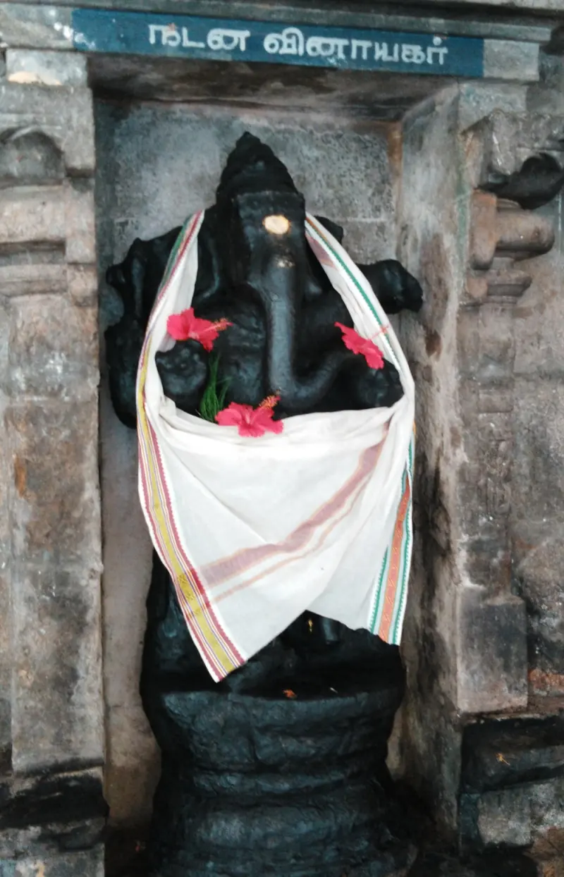 A black dancing Vinayakar idol with flowers and a cloth