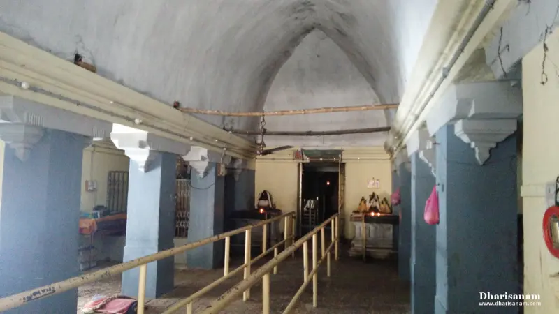 A long hall with blue and white pillars, a vaulted white ceiling and a railed path toward a lit shrine at the far end