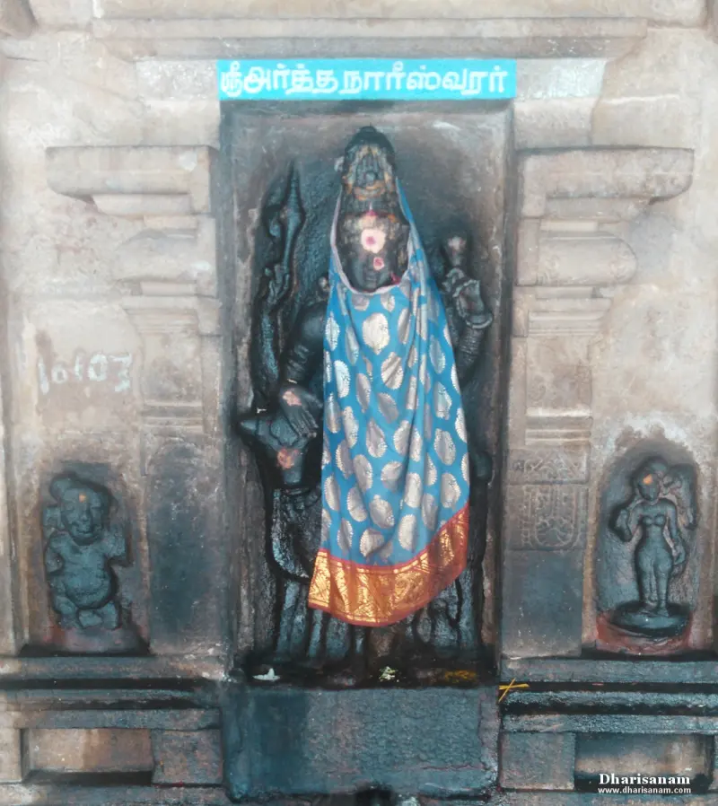 Black stone Ardhanareeswarar idol draped in a blue sari, in a niche with a Tamil name board