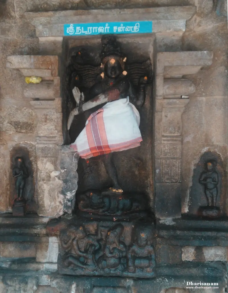 Dancing black stone idol of Natarajar in a niche, with carved figures below