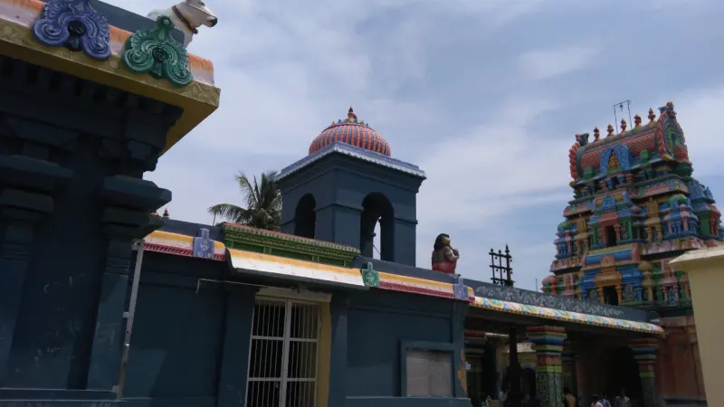 A dark blue shrine wall with a small domed turret, and a colourful tower on the right