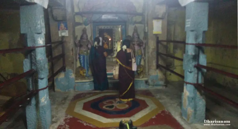 Women praying before a lamp-lit shrine doorway with idols on either side