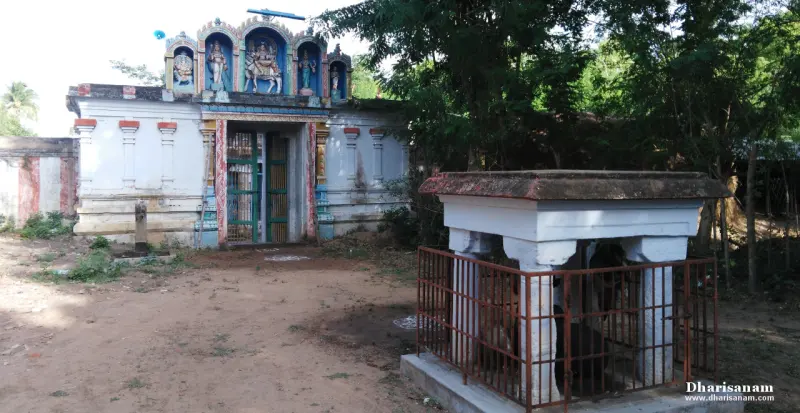 The temple entrance with painted figures above, and a small railed stone shrine on pillars in the foreground