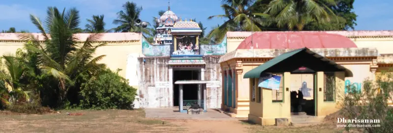 A gateway with a painted sculpture above it, yellow walls on either side and a shed to the right