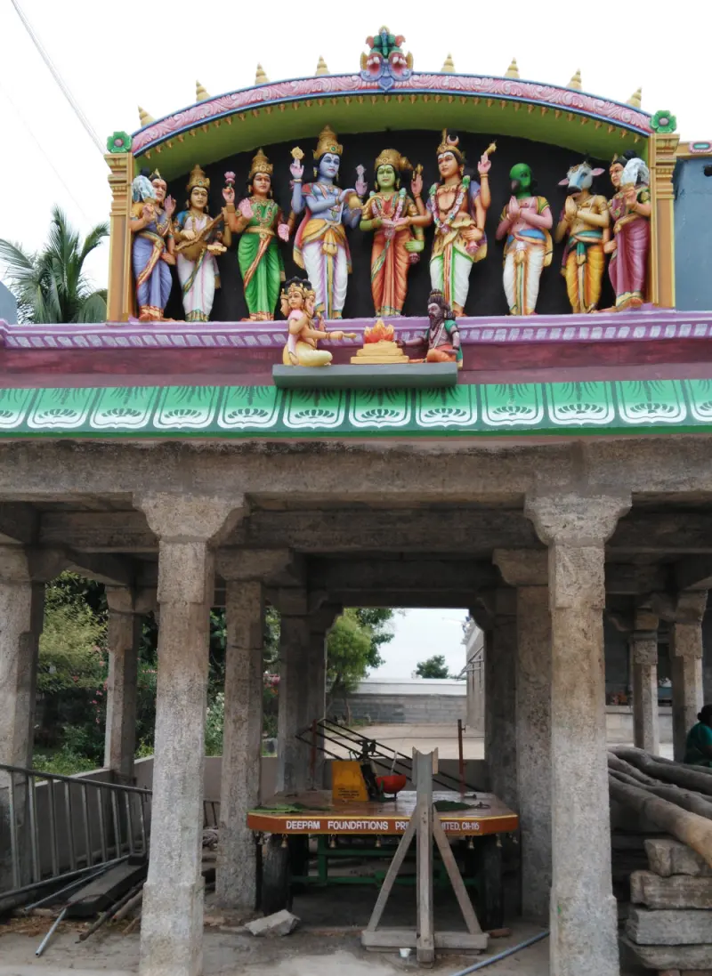 Row of nine colourful deity statues above a stone pillared hall