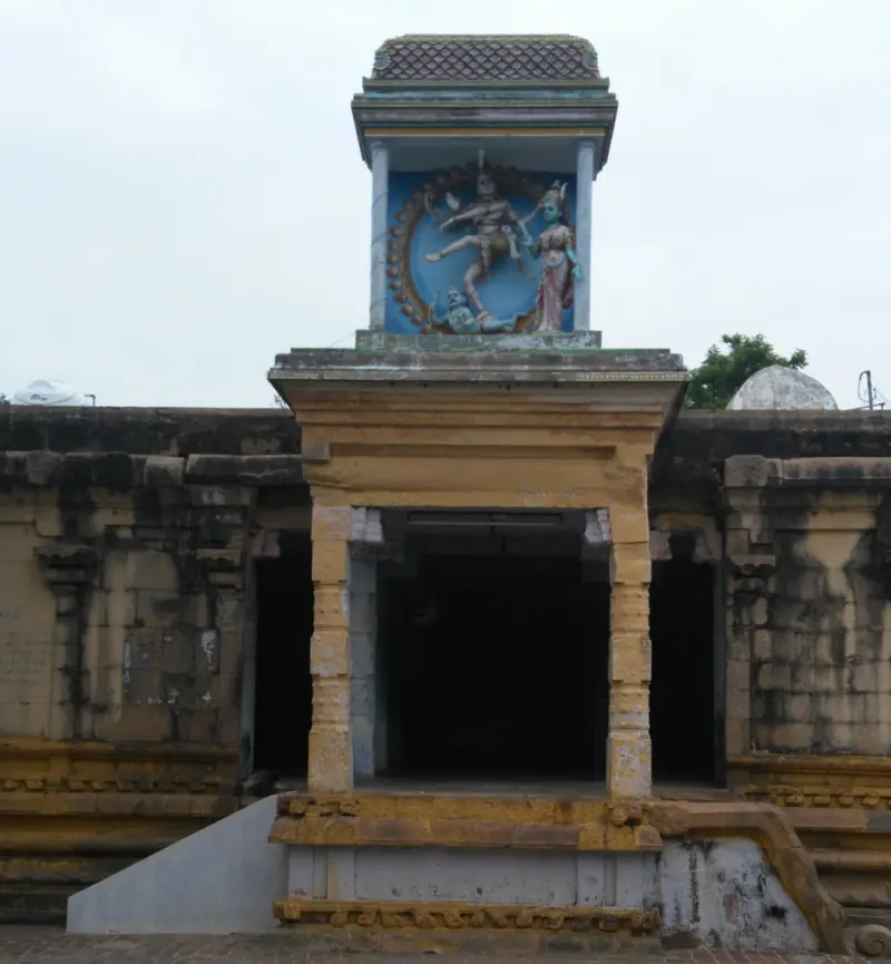 A stone porch with a tower above holding a painted relief of a dancing deity beside a goddess.