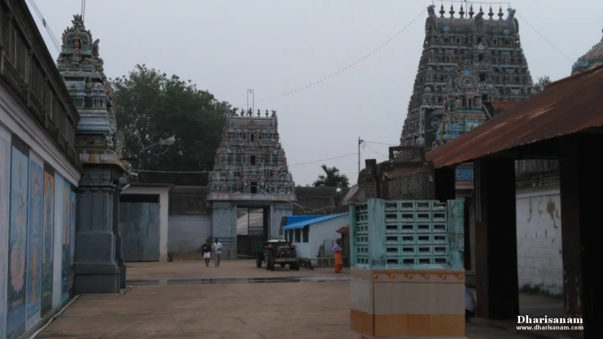 Two gateway towers and a courtyard with a few people walking, painted panels on the wall at the left