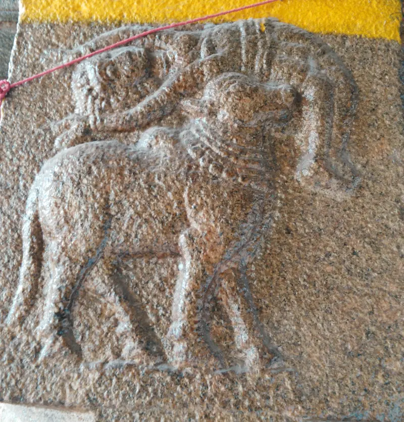 A bull carved in low relief on a granite panel, tied with a red thread