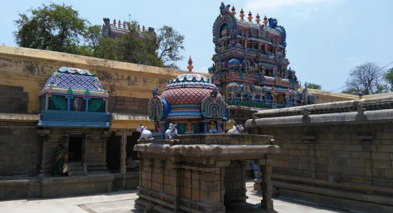 Painted shrine domes with bull statues inside the walls, and a tiered tower rising above the trees
