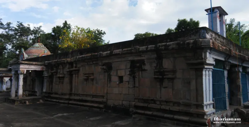 A long carved granite wall with a small domed tower at the far left and an open paved courtyard