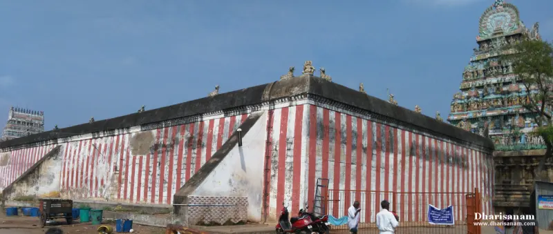 A long wall painted in red and white stripes, with a colourful tower rising behind its corner