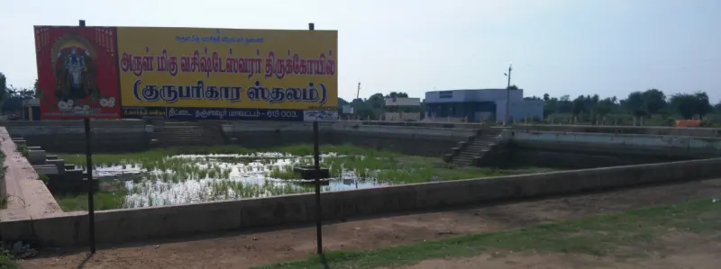 Shallow tank with steps and a red board naming the Guru Parikara temple