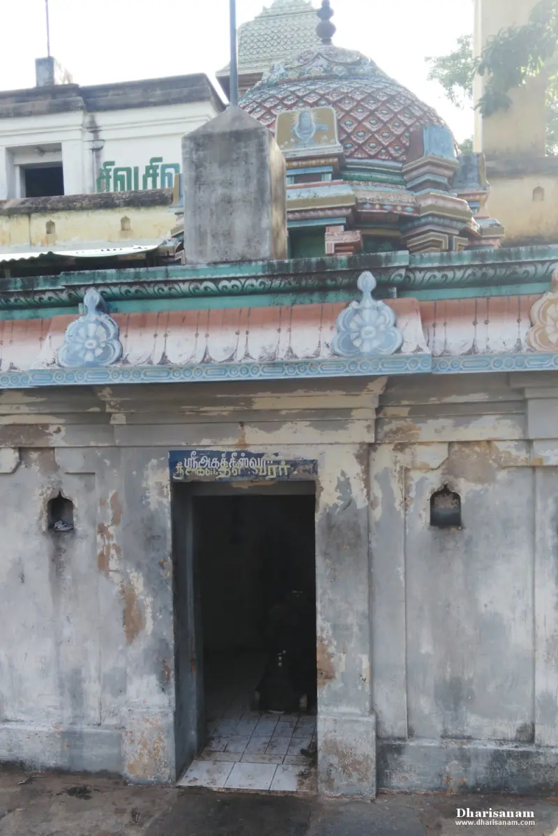 A weathered shrine with a patterned dome above, a Tamil name board over a dark doorway