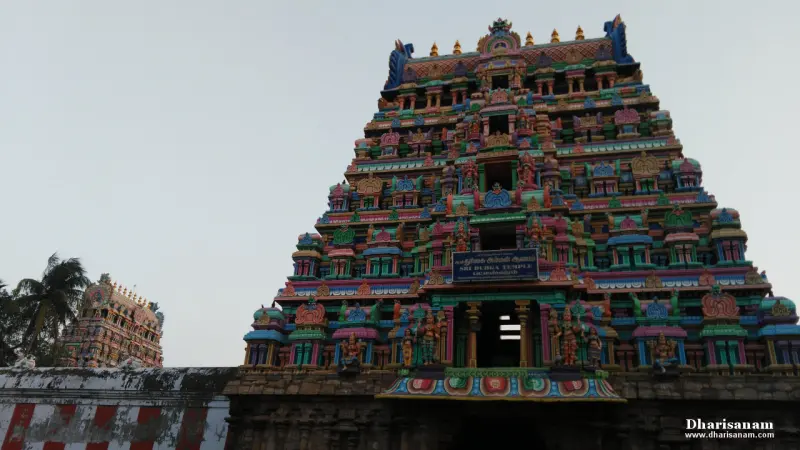 A colourful tiered gopuram under a blue board naming the Durga temple, with another tower at left