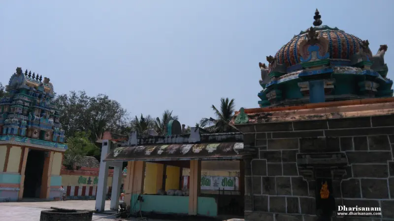 A temple tower at the left and a domed stone shrine at the right, with an open pillared hall and coconut palms between