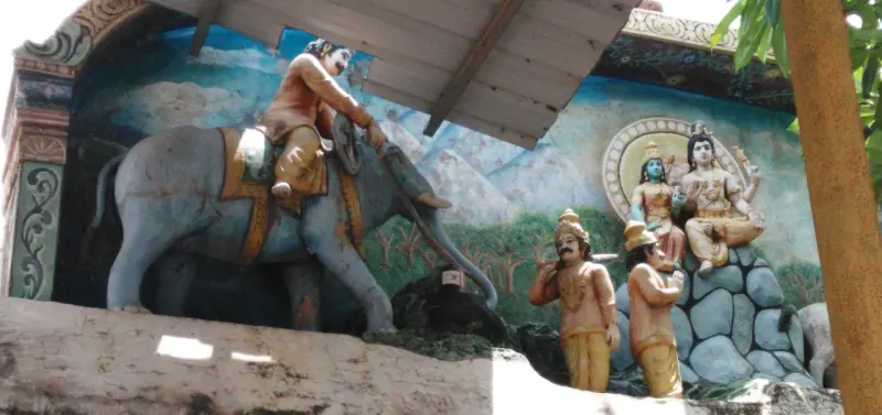 A painted tableau of a man riding an elephant, two standing men, and a seated divine couple on rocks.