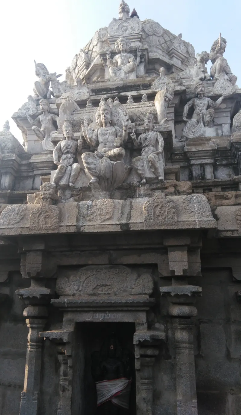 A stone shrine doorway with a dark idol inside and many sculpted figures on the tower above