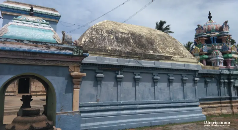 Blue stone temple wall with a domed roof, a small painted tower on the right and an arched opening on the left