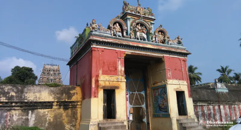 A red and yellow gateway with a small tiered tower, and a taller temple tower behind it on the left