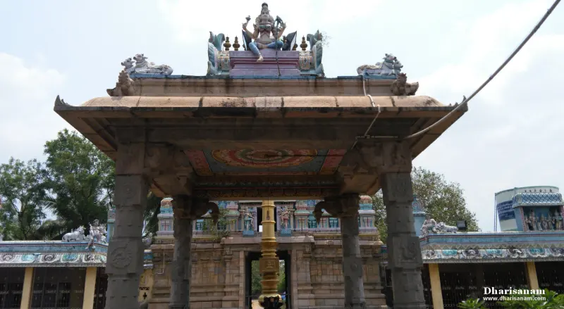Open pillared mandapam topped by a painted figure, with the flag post beyond