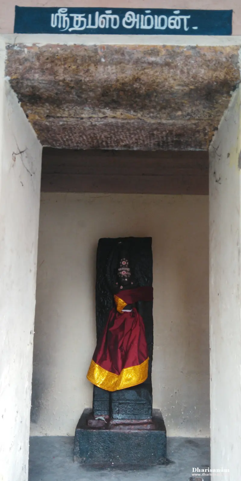 Standing goddess in red silk with hand on head in a small shrine