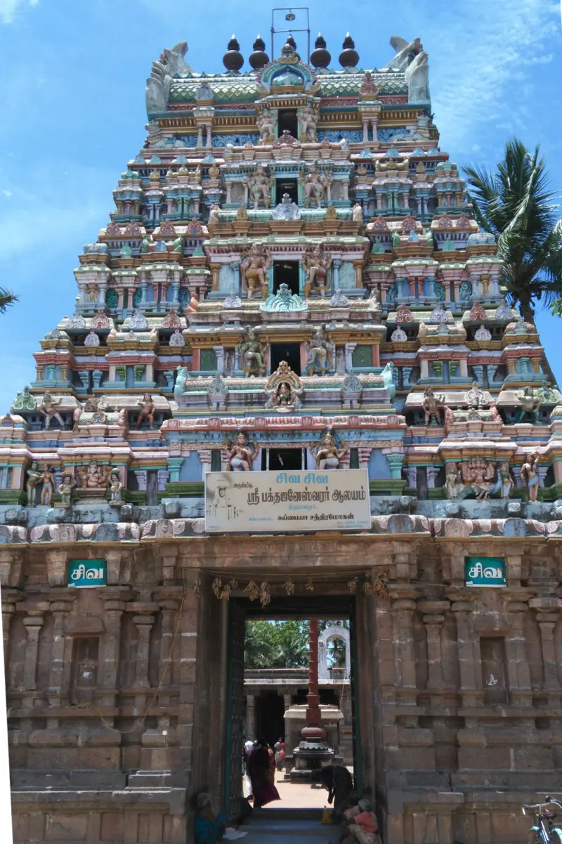 A painted tiered tower above a stone gateway with a name board; the inner courtyard shows through the doorway.
