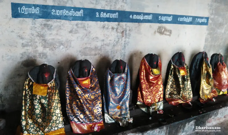 Seven cloth-draped idols in a row under a name board