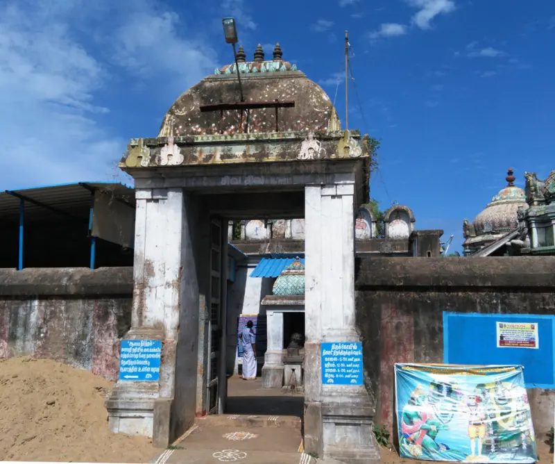 Weathered stone gateway with dome, notice boards and a festival banner