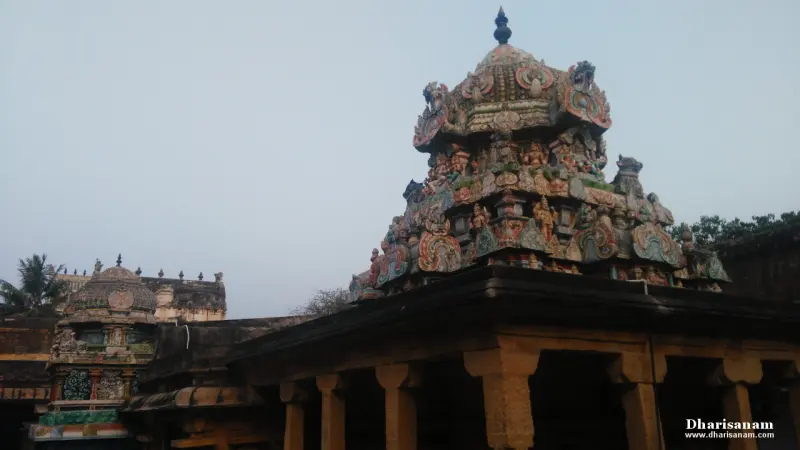 A painted tower top with many figures rises above a pillared hall, with a smaller tower beyond.