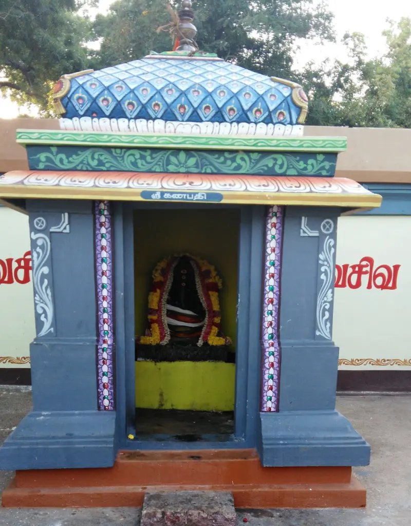 A small blue and orange shrine with a garlanded idol inside; the sign above reads Sri Ganapathi.