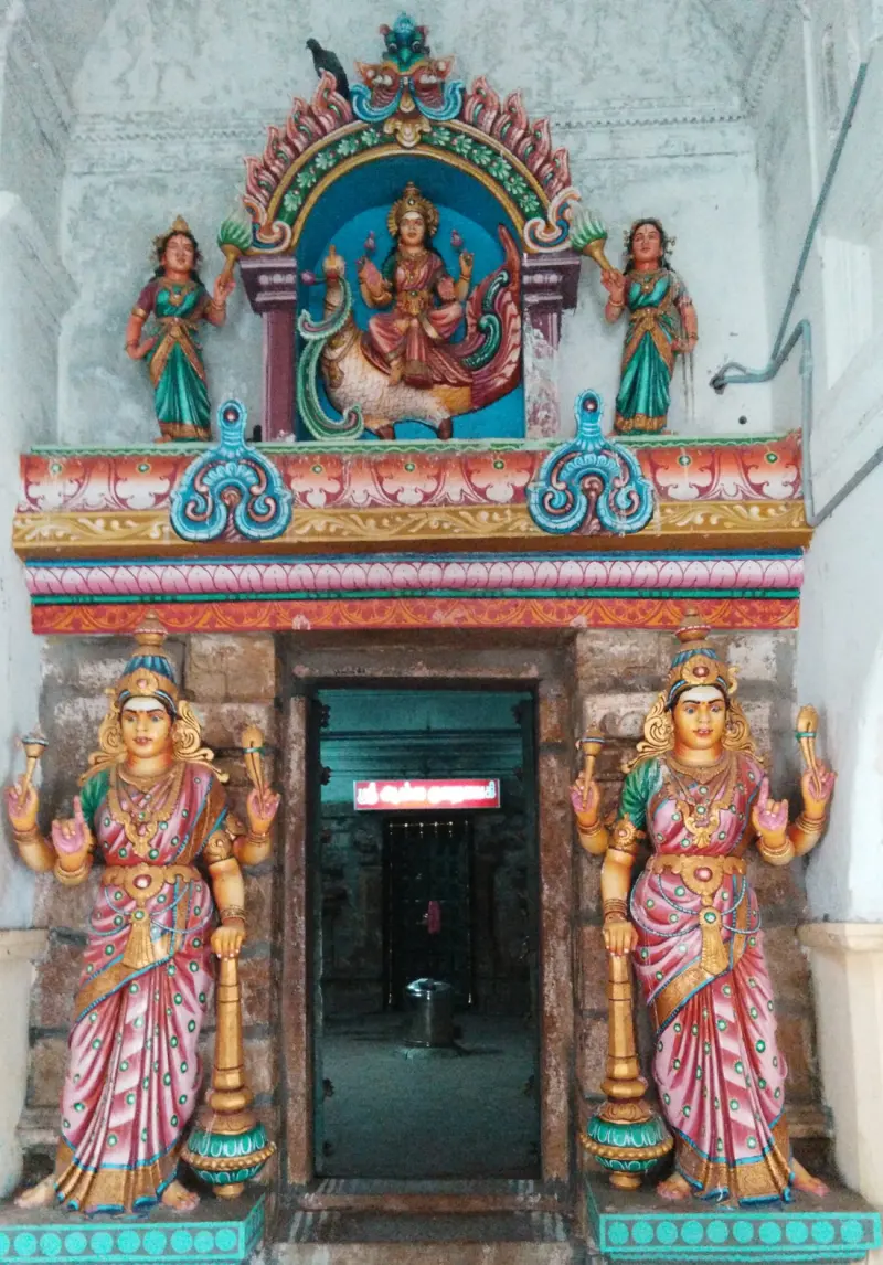 Painted shrine entrance with two standing women on either side and a seated goddess above