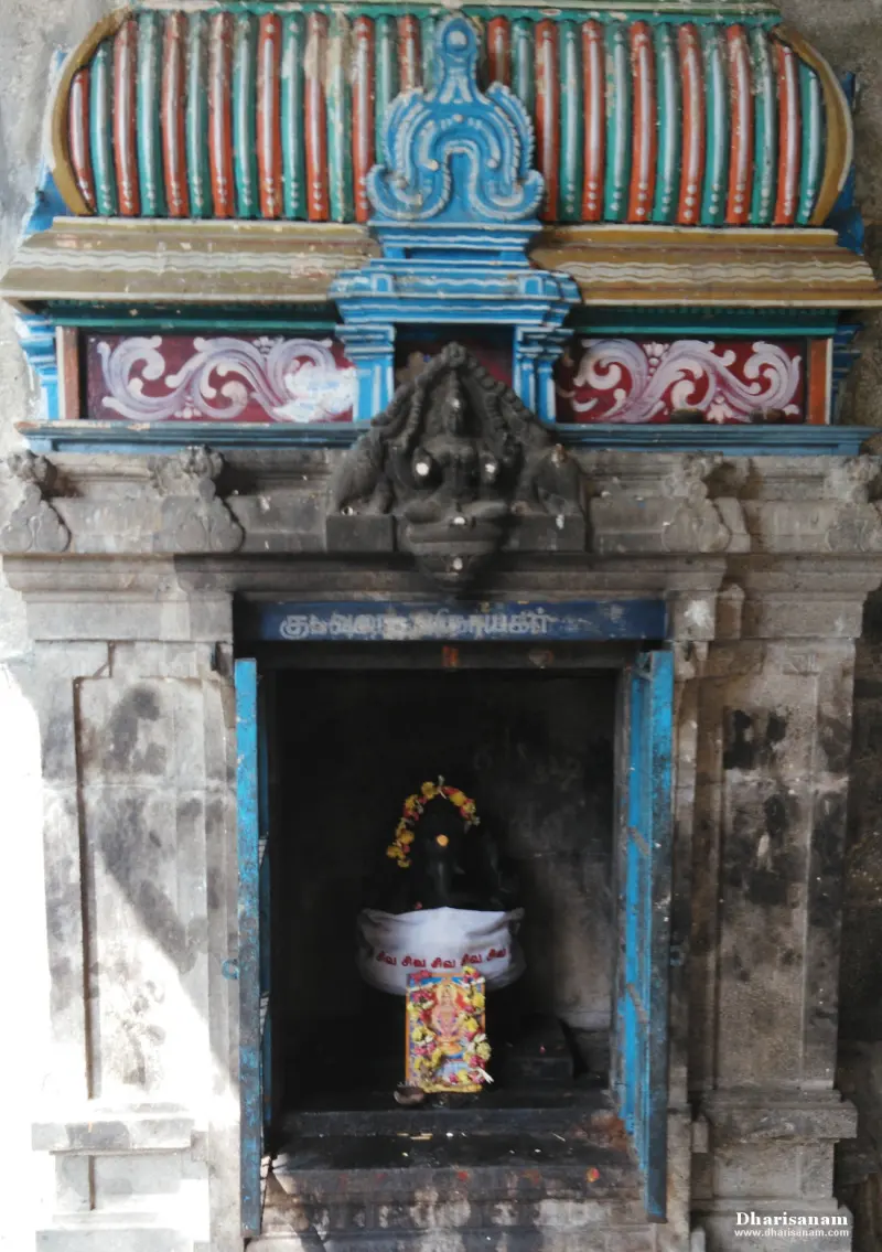 Garlanded Ganesha idol in white cloth inside a painted stone shrine