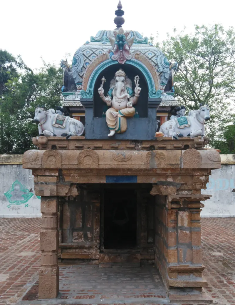 Small stone shrine with a painted Vinayakar above the door and a bull on each side