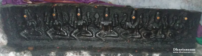Dark stone relief panel showing a row of seated figures, each with a small lit lamp before it