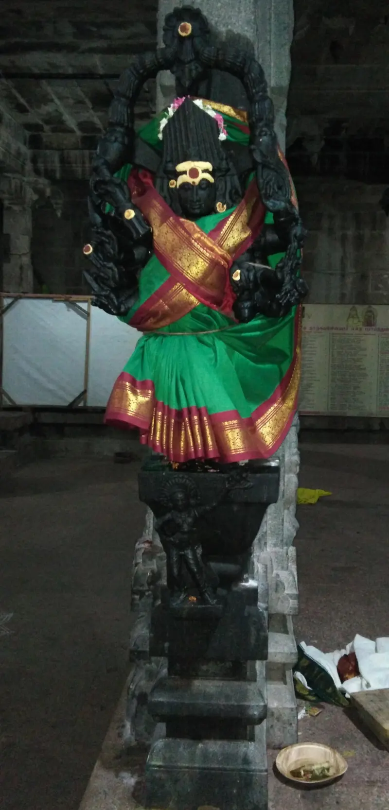 A figure on a pillar dressed in a green sari