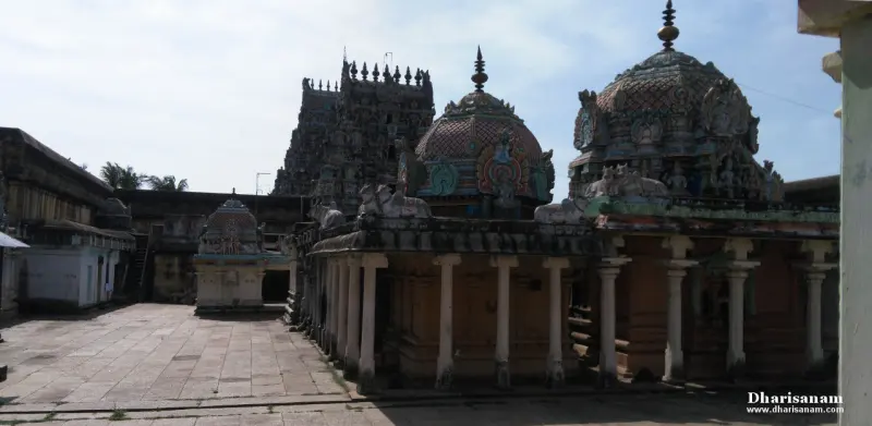 A paved courtyard with a pillared hall and domed shrine roofs, and a tower behind