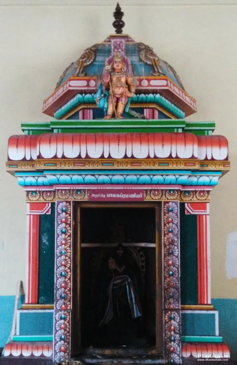 Colourful shrine topped by a standing figure, with a Tamil name board above the door