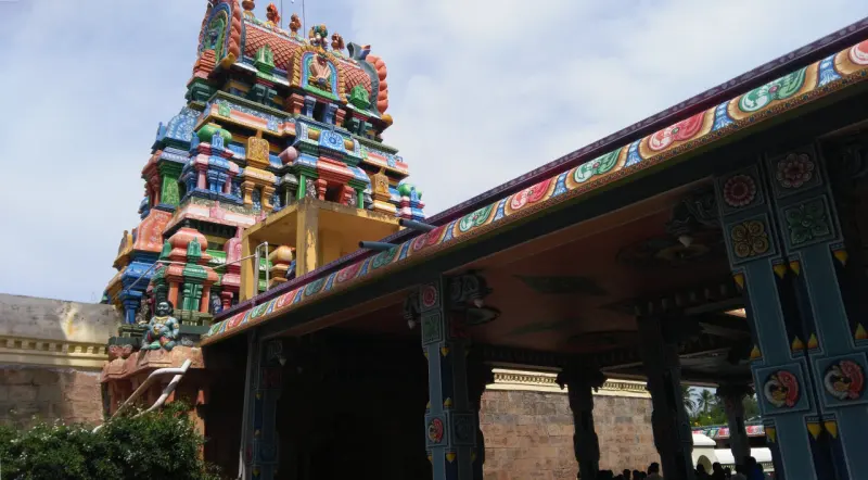 A colourful tower seen from beneath the painted roof of a pillared hall