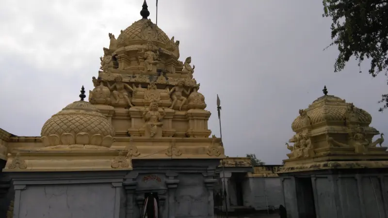 A cream-coloured tower with carved figures above the sanctum, and a smaller domed tower to its right.