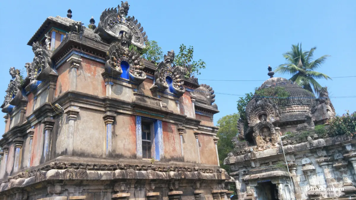 Two weathered shrine towers with carved corner figures against a blue sky