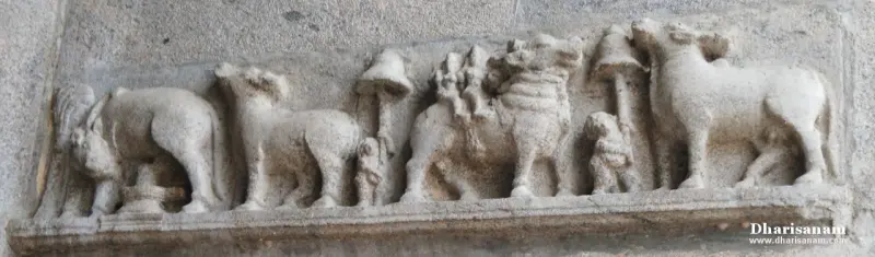 A long stone relief of cows, a lion-like animal and small figures along a narrow ledge
